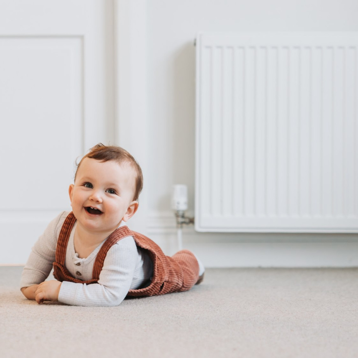 Child safely playing in front of a gas radiator.