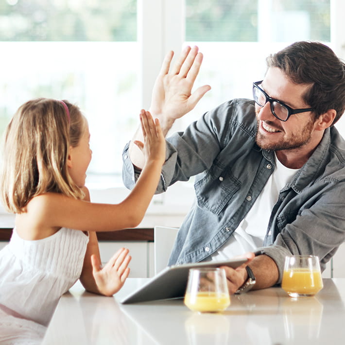 Father and daughter at kitchen table high five for free gas connection