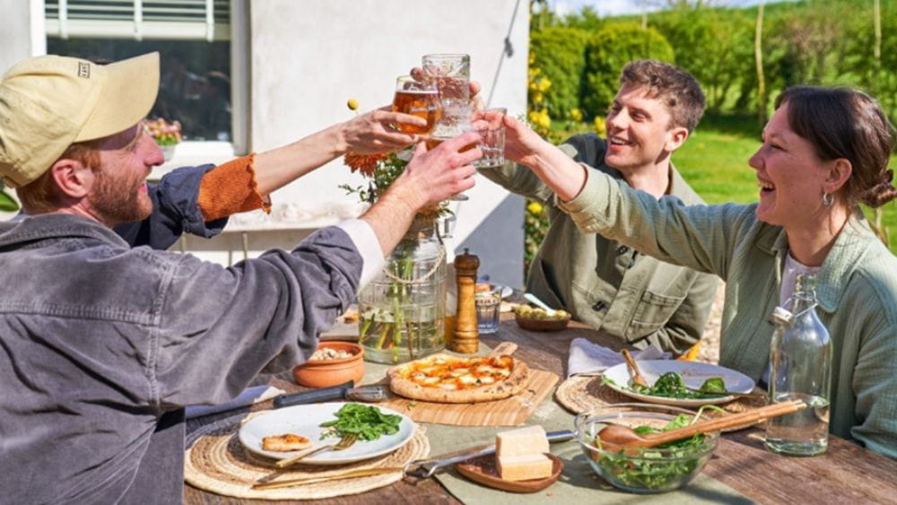 A group of people cheersing over homemade pizza.