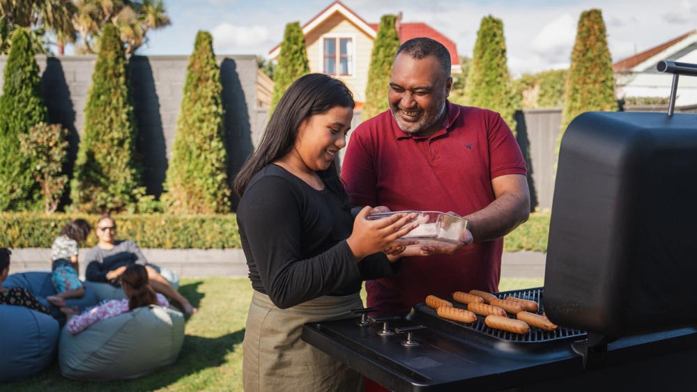 Father and daughter cooking on a gas bbq