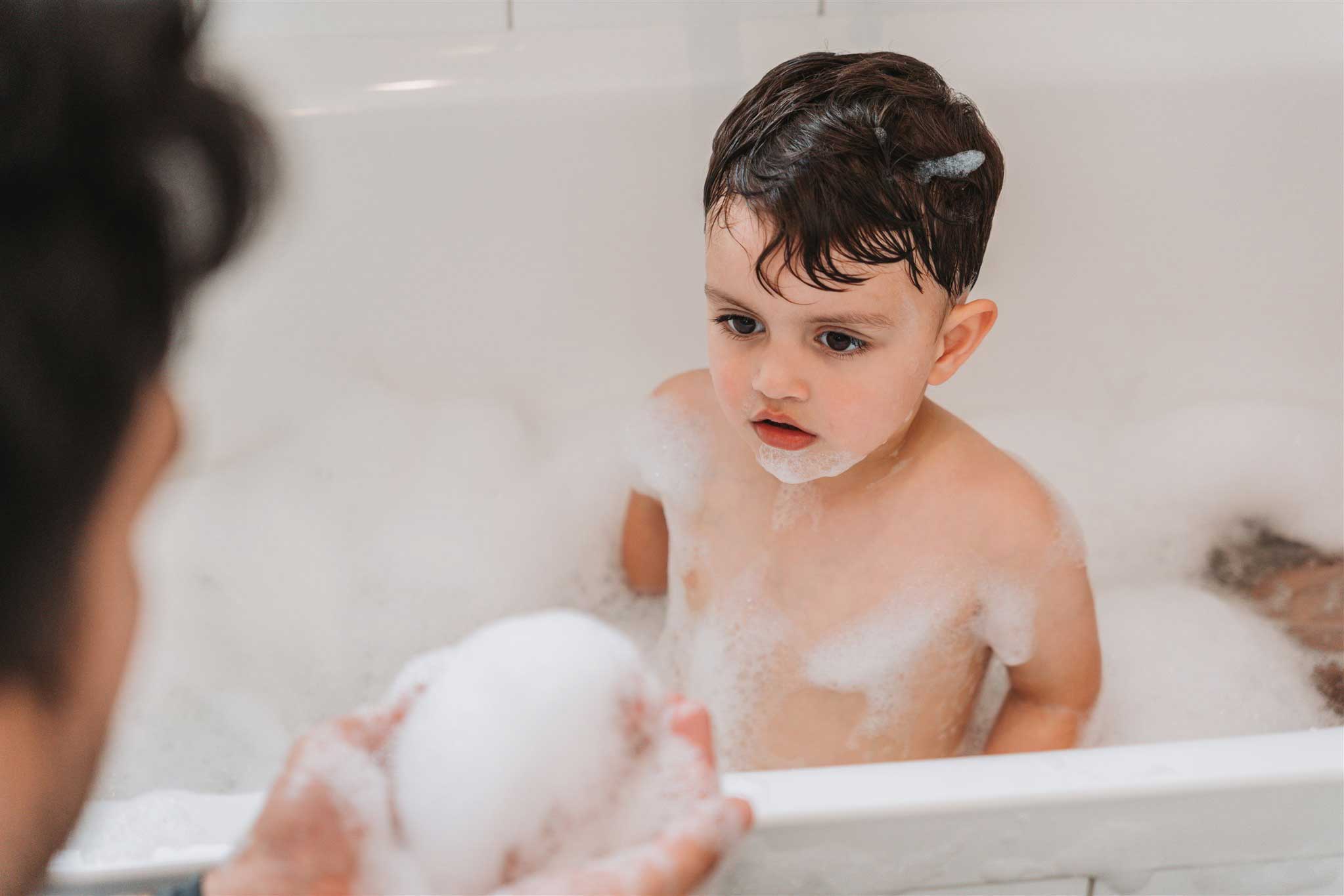 Young child playing with bubbles in bath