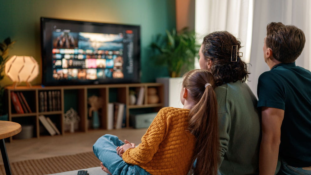family sitting on couch watching tv