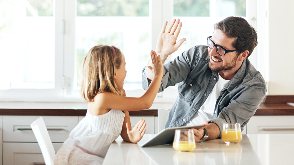 Father and daughter at kitchen table high five for free gas connection